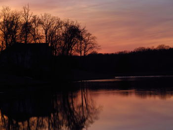 Silhouette trees by lake against sky at sunset