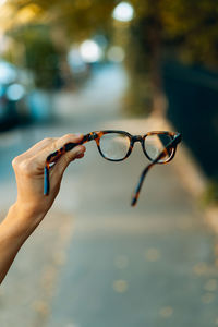 Close-up of hand holding eyeglasses against blurred background