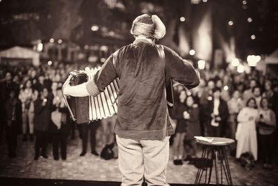 Rear view of man playing accordion in front of audience