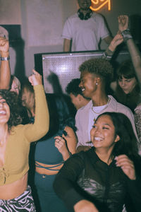 Cheerful young multiracial men and women dancing at nightclub