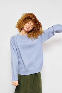 Portrait of young woman standing against white background