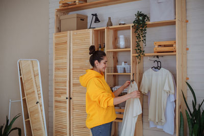 Woman at home sits on the floor on a wardrobe trunk near the closet and puts towels in the basket