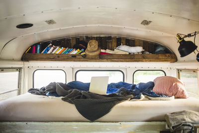 Laptop and crumpled blanket on bed in camper vehicle