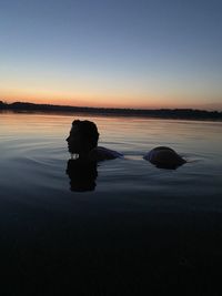 Woman swimming in sea against sky during sunset