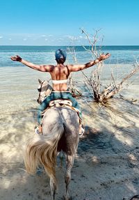 Full length of shirtless man at beach against sky