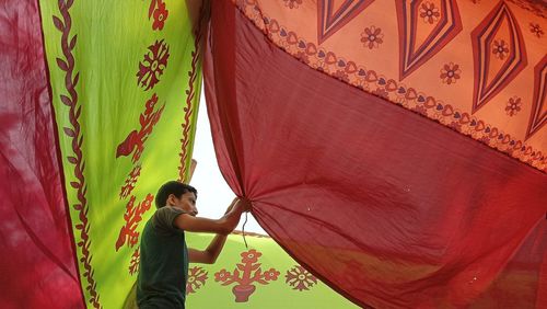 Side view of woman standing against curtain