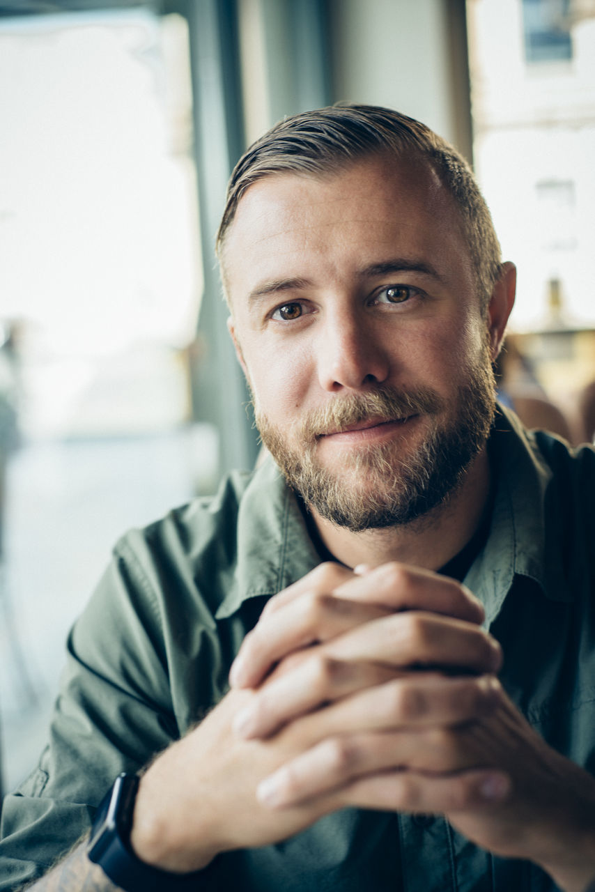 young men, lifestyles, person, focus on foreground, front view, portrait, leisure activity, indoors, looking at camera, headshot, casual clothing, young adult, holding, waist up, beard, handsome, close-up, mid adult