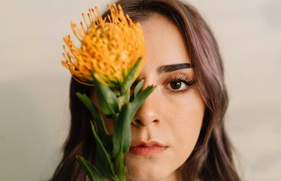 Close-up portrait of a beautiful young woman with yellow flower over white background