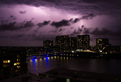 Illuminated buildings in city against sky at night