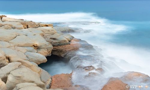 Scenic view of rocks in sea against sky