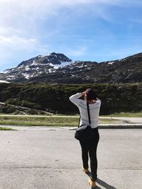 Rear view of woman walking on road against mountain