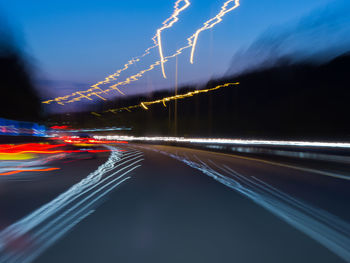 Light trails on road against sky at night