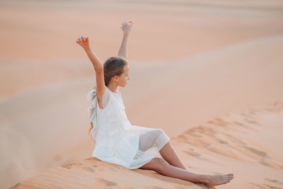 Full length of woman sitting on sand at beach