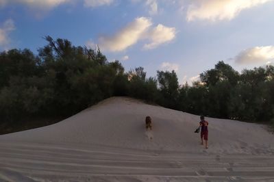 People on sand dune against sky