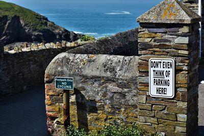 Information sign on wall by sea