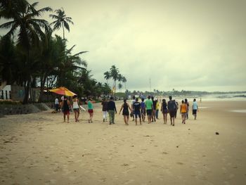 People on beach against cloudy sky