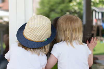 Rear view of girls standing by window