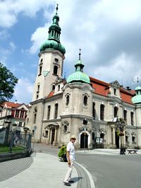 Side view of senior man standing on road against church in city during sunny day