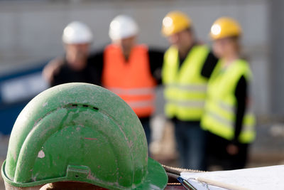 Close-up of hardhat against engineers at construction site