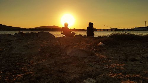 People on beach against sky during sunset