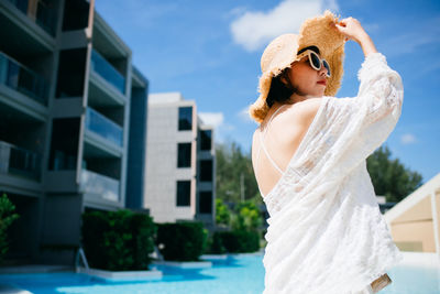 Woman wearing sunglasses standing by swimming pool