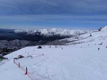 People skiing on snowcapped mountain against sky