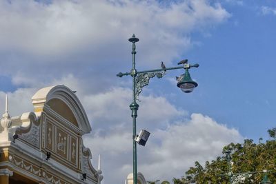 Low angle view of street light by building against sky