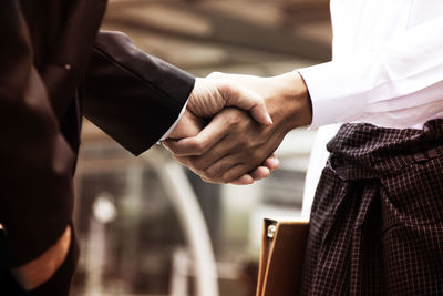 Midsection of business people giving handshake at office