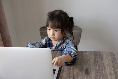 Girl looking away while sitting on table