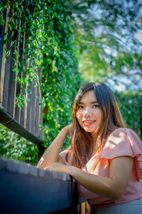 Portrait of a smiling young woman against trees