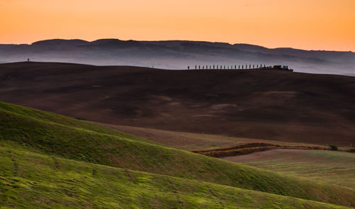 Scenic view of landscape against dramatic sky during sunset