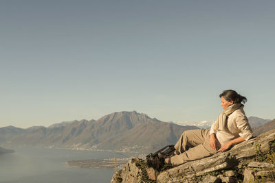 Female hiker lying on cliff against swiss alps