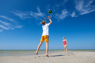 Full length of friends enjoying at beach against sky