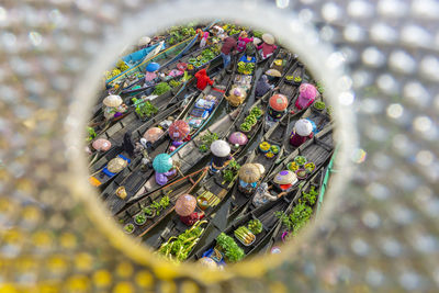 People selling food in boats seen through hole