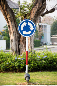 Road sign by tree on field