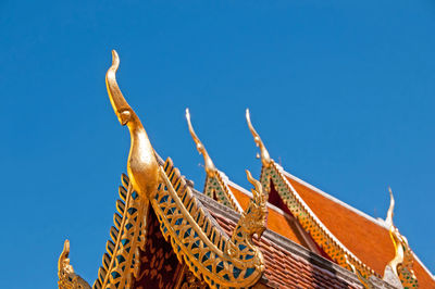 Low angle view of temple against building against clear blue sky