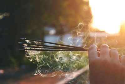 Cropped hand holding burning incenses