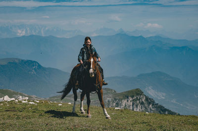 Portrait of boy riding horse against mountains