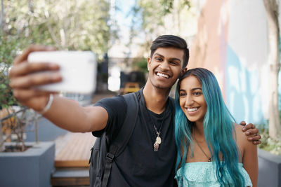 Portrait of smiling friends using mobile phone