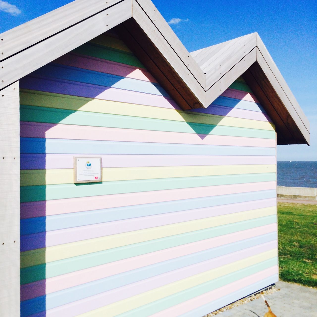 blue, built structure, architecture, building exterior, sunlight, shadow, clear sky, day, window, pattern, no people, sky, multi colored, outdoors, wall - building feature, striped, low angle view, sunny, wall, absence