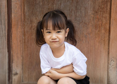 Portrait of girl crouching by wall