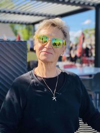 Portrait of young looking  proud older  woman wearing sunglasses while sitting on a patio for lunch.  