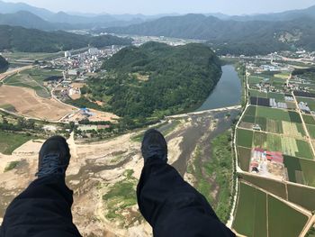 Low section of person paragliding over landscape