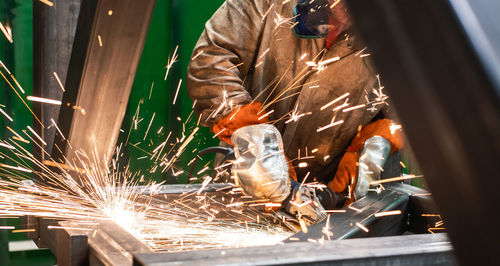 Midsection of welder welding metal in workshop