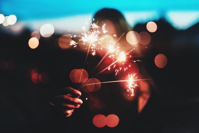 Woman holding lit sparklers at night