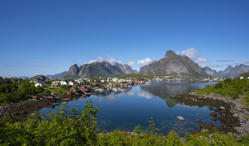 Scenic view of lake and mountains against clear blue sky