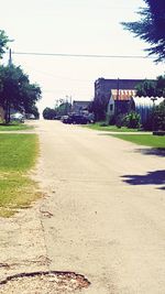 Road by buildings against clear sky