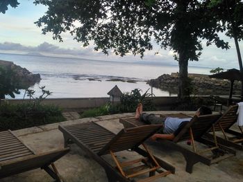 People sitting on chair by sea against sky