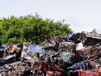 Stack of garbage by trees against sky