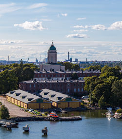 Boats in river by buildings against sky